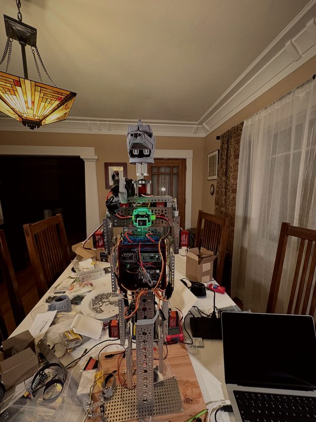 The early aluminum skeleton standing on the dining-table workbench under a stained-glass lamp