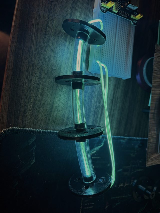 A glowing cyan light tube threaded through black servo discs, lit in the dark