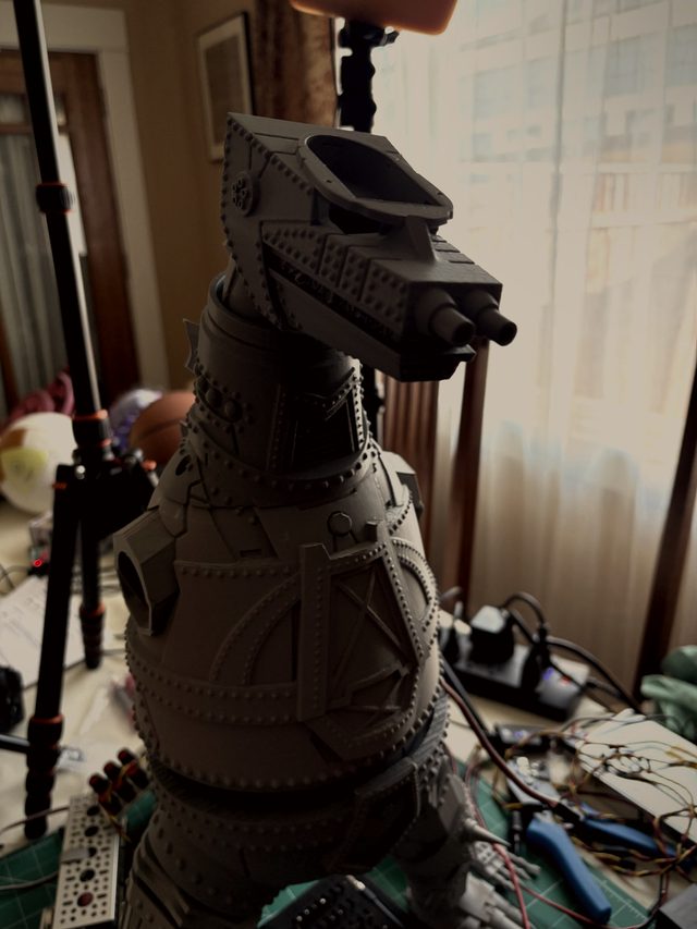 Unpainted gray 3D-printed MechaGodzilla head and riveted torso, three-quarter view on a workbench