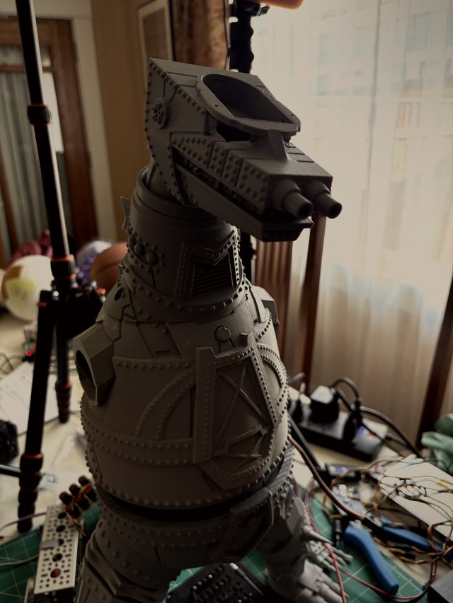 MechaGodzilla head and riveted torso by a window, wiring and tools on the workbench below