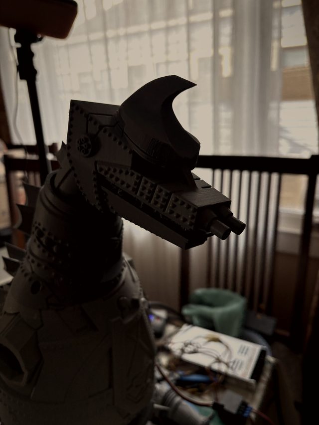 Close-up profile of MechaGodzilla's head with crest horn and twin snout cannons, backlit by a window
