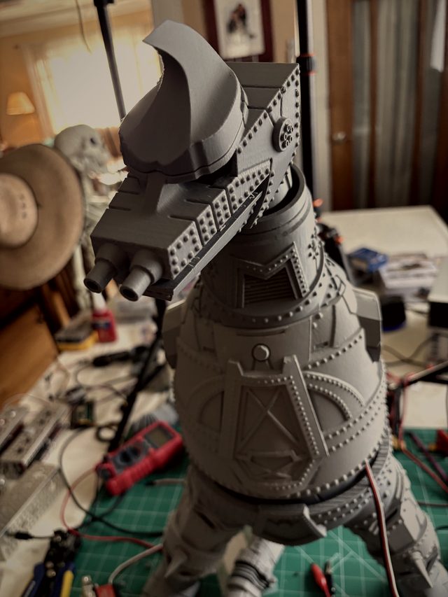MechaGodzilla's crested head and riveted chest armor in close-up over the workbench