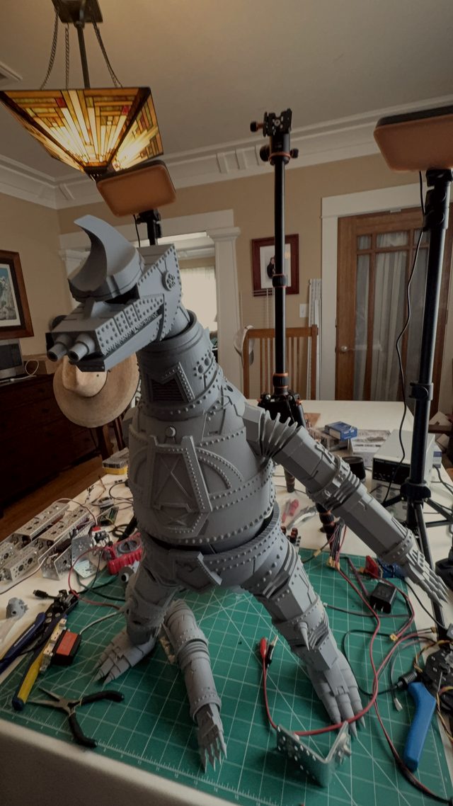 Tall front view of MechaGodzilla standing under a lamp with detached hands on the cutting mat