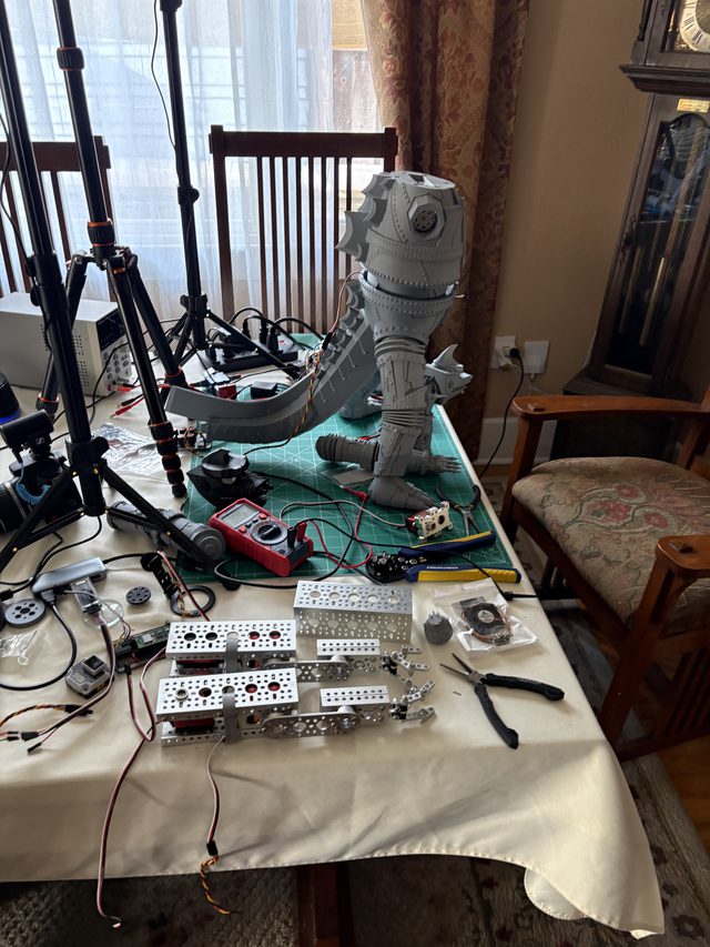 Workbench overview: headless MechaGodzilla lower body and tail on a cutting mat with tools