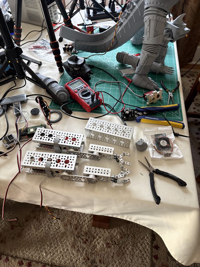 Disassembled parts on the bench: tail section, leg, and servo-mounted aluminum brackets