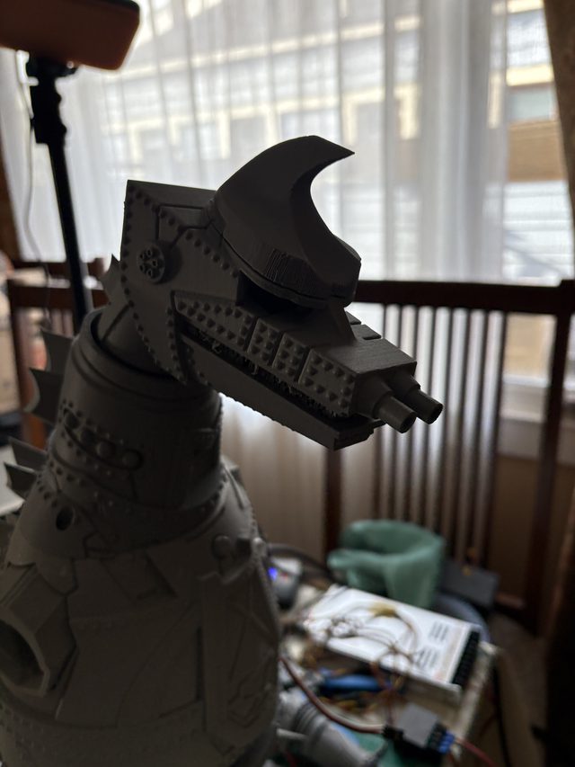 Close-up profile of MechaGodzilla's head with crest horn and twin snout cannons, backlit by a window