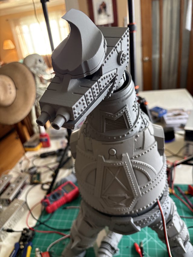 MechaGodzilla's crested head and riveted chest armor in close-up over the workbench