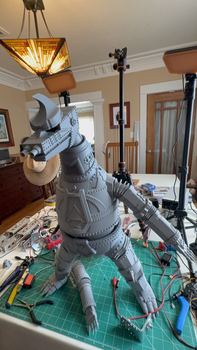 Tall front view of MechaGodzilla standing under a lamp with detached hands on the cutting mat
